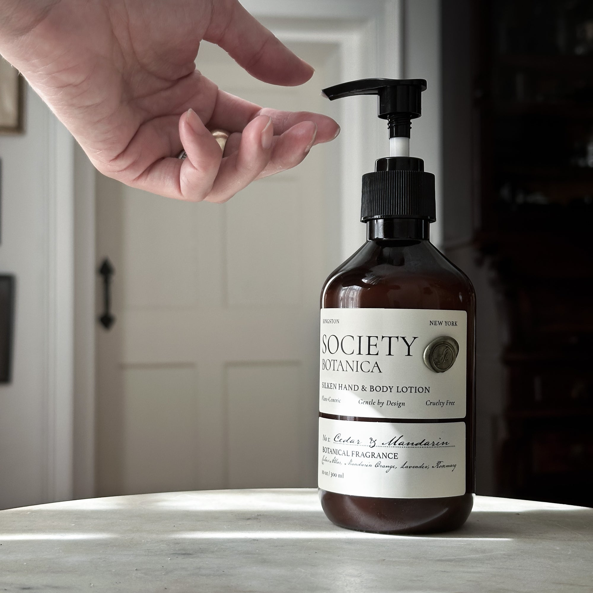 Society Botanica lotion bottle on a surface with a blurred background